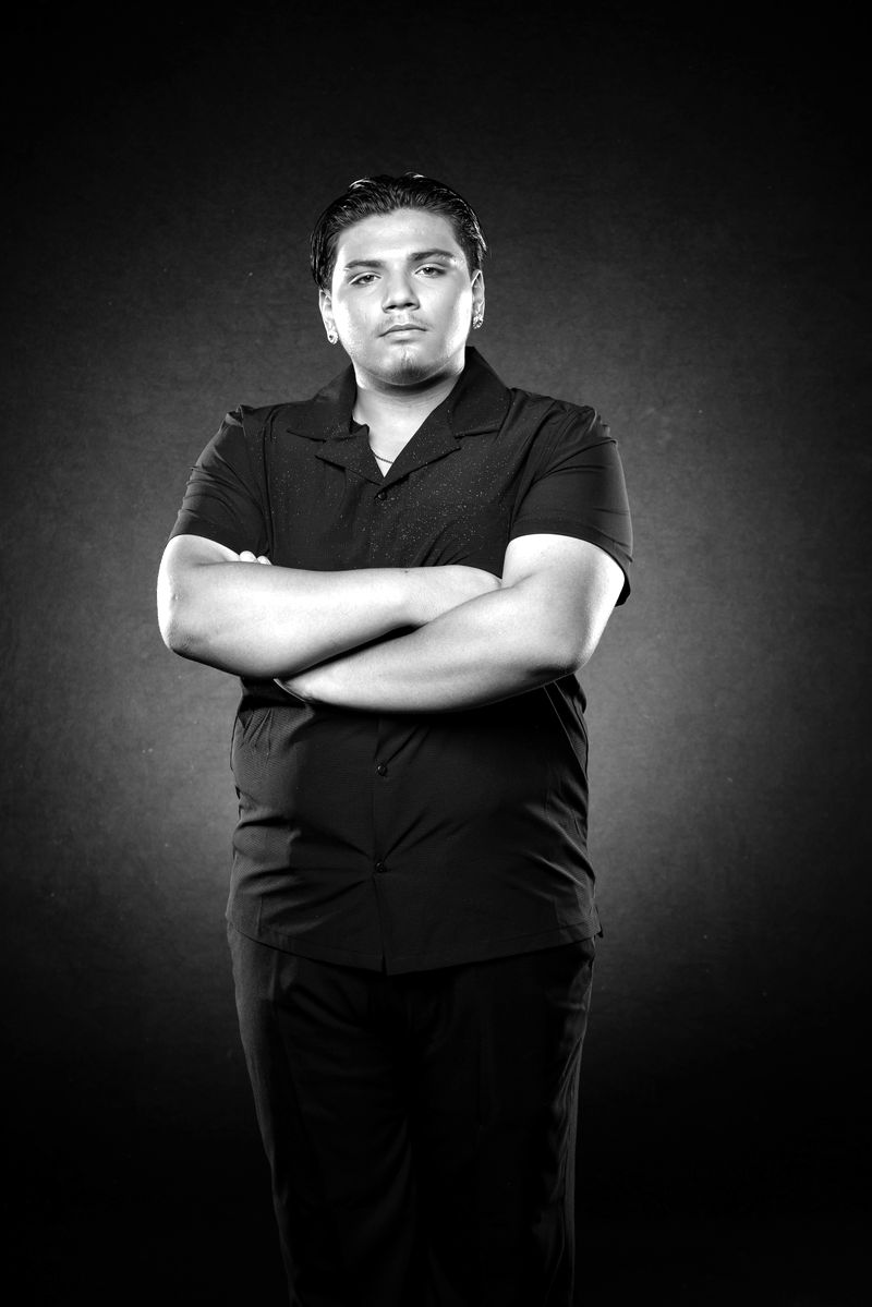 Morgan Hernandez, arms crossed, in a black studio portrait.